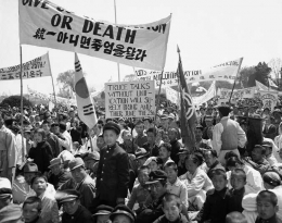 Civilians and soldiers stood beneath a banner during a demonstration in Seoul in April 1953 against resumption of the Korean peace talks.