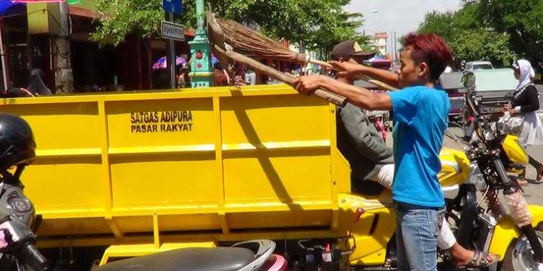 Lanang (20) memasukkan sampah kedalam bak saat melakukan pekerjaannya menjadi tukang sapu di Komplek Pasar Brebes, Senin (2/5/2016) (Kompas.com/Ari Himawan Sarono) 
