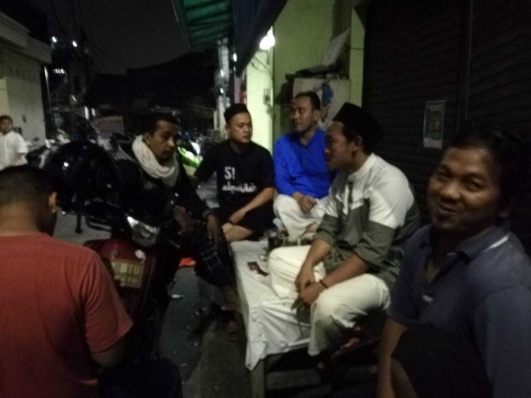 LMK RW 08 Kelurahan Jati Pulo Muhamad Ridwan (tengah-berbaju biru) bersama warga masyarakat dan tokoh agama Ustadz Ilham Junaedi sedang ronda sambil diskusi