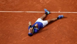 Rafael Nadal meluapkan kegemberiaan dengan berbaring di lapangan tanah liat pada turnamen Perancis Terbuka 2017 (Sumber: edition.cnn.com).