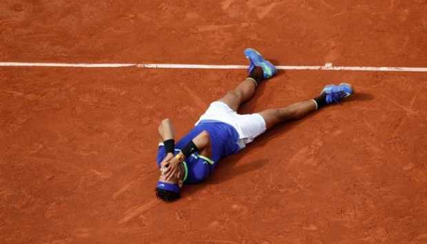 Rafael Nadal meluapkan kegemberiaan dengan berbaring di lapangan tanah liat pada turnamen Perancis Terbuka 2017 (Sumber: edition.cnn.com).