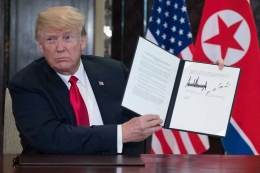 Presiden AS Donald Trump menunjukkan dokumen yang memuat tanda tangannya dan pemimpin Korea Utara Kim Jong Un usai perundingan di Singapura, Selasa (12/6/2018). 