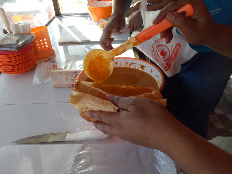 Tampak seorang pekerja bagian pelayanan penjualan sedang mengolesi sele pada roti yang telah dibelah menggunakan sendok khusus. (foto: koleksi pribadi)