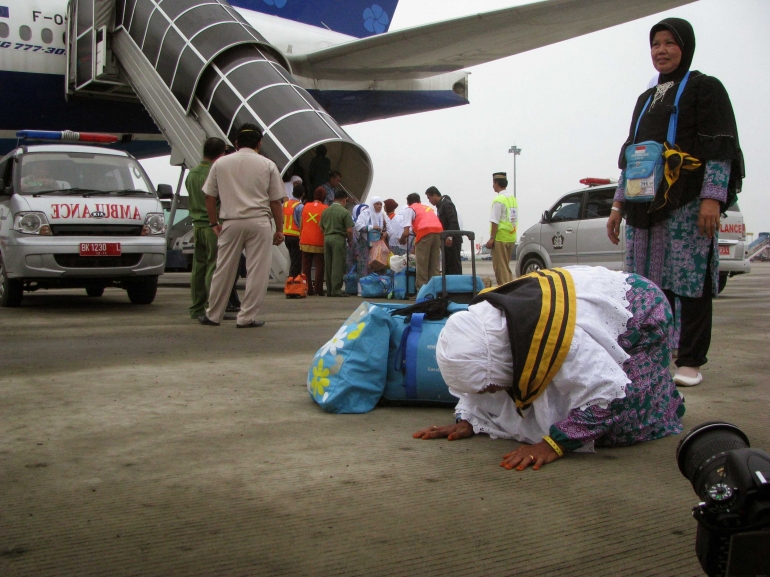 Seorang jemaah haji setibanya di tanah air bersujud sebagai ungkapan syukur di Bandara Kualanamu. Foto | Dokpri