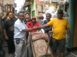 Ketua RW 03 Palmerah H. Nurhadi Prayitno (baju putih) menyerahkan bantuan material bagi korban kebakaran yang diterima Ketua RW08 Palmerah Imam Solikin (baju kuning)