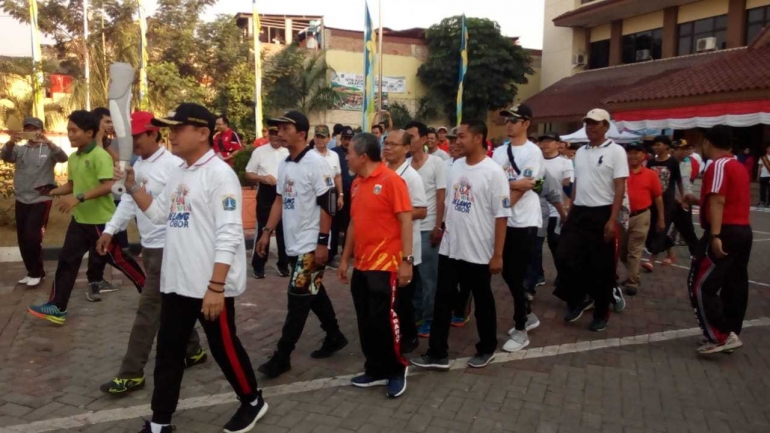 Camat Palmerah Zeri Ronazy didampingi Sekcam Bambang Sutarno mengusung replika obor Asian Games 2018