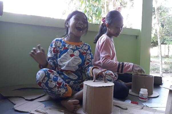 Seorang anak dari Kelompok Bentangor Kids terlihat tertawa lepas karena ia berhasil membuat topi. Foto dok. Yayasan Palung