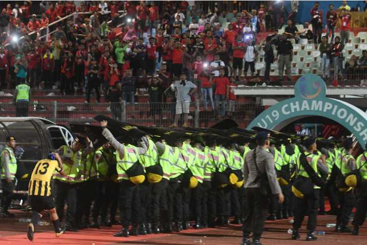 Petugas keamanan berusaha melindungi pemain Malaysia dari lemparan suporter Indonesia