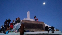 Bulan pun masih ada. Wisatawan menanti detik-detik matahari terbit dari monumen dan tugu di puncak Gunung Kelimutu. (Foto: Gapey Sandy)