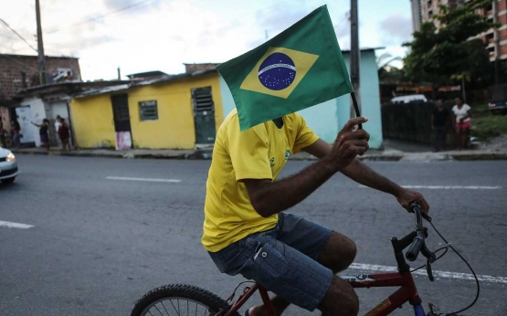 Warga Rio de Janeiro mengibarkan bendera Brazil sambil bersepeda keliling kota saat Olimpiade Rio 2016. Foto: Telegraph.