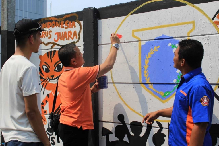 Camat Palmerah Zeri Ronazy melukis mural disaksikan Ketua Karang Taruna Jati Pulo Agus Setiawan dan Lurah Jati Pulo Ari Kurnia
