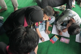 Salah satu anggota KKN59 UMM mendampingi peserta Lomba Mewarnai Kaligrafi | dokpri