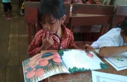 ekspesi serius anak ketika melihat dan membaca buku cerita. Foto dok : Yayasan Palung