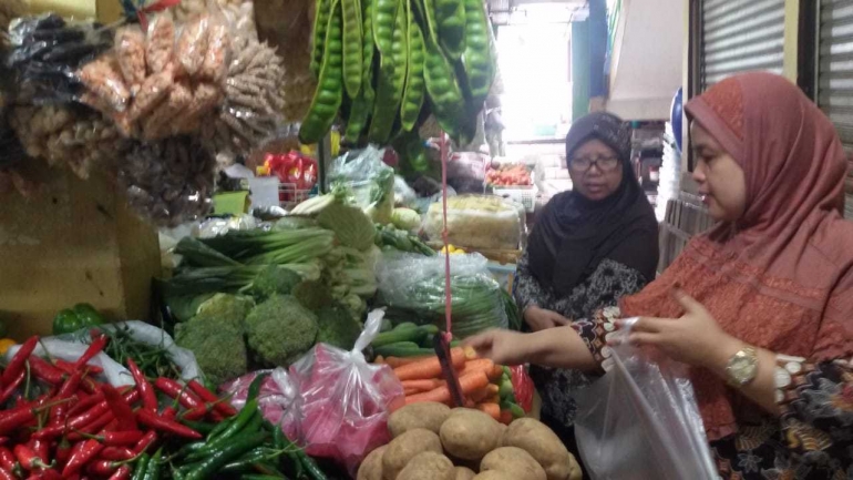 Ibu Hanna, pedagang sayur tengah melayani pelanggan. Foto | Dokpri