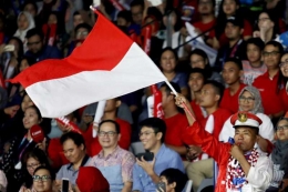 Seorang suporter Indonesia mengibarkan bendera merah putih untuk memberikan dukungan kepada atlet bulu tangkis Indonesia yang tengah bertanding pada babak penyisihan Asian Games 2018, di Istora Senayan, Jakarta, Jumat (24/8/2018).( ANTARA FOTO/INASGOC/Nafielah Mahmudah) (INASGOC/NAFIELAH MAHMUDAH)