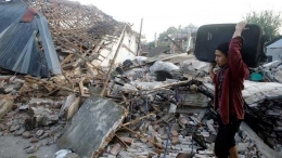 Seorang pria melihat rumahnya yang hancur akibat gempa bumi di Lombok Utara, 9 Agustus 2018. Gempa Lombok, yang diikuti gempa susulan yang terjadi berkali-kali, membuat rumah warga rusak ringan hingga berat. (Sumber: tekno.tempo.co/AP)