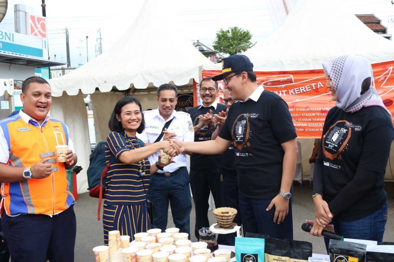 Vice President Daop 5 Purwokerto, Mohamad Nurul Huda Dwi Santoso menyerahkan segelas kopi racikannya kepada penumpang kereta api.