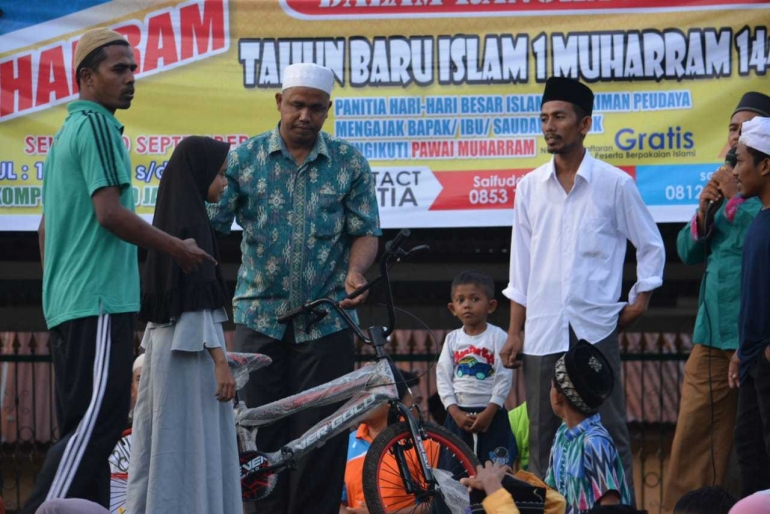 Ketua PHBI Kemukiman Peudaya Tgk Usman Zakaria saat menyerahkan hadiah sepeda gunung kepada peserta zikir keliling yang berhasil mendapatkan hadiah utama (dok. Maulana Marwan, ST) 
