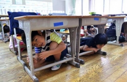 Budaya sadar bencana bisa ditanamkan sejak dini seperti berlindung di kolong meja kayu saat gempa (Photo: jpninfo.com)