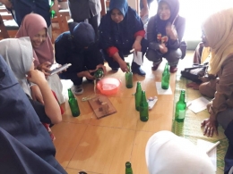 Peserta pelatihan dan sosialisasi pengelolaan sampah yang terdiri dari Ibu PKK sedang membuat gelas dari botol kaca bekas