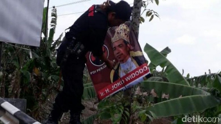 Kader PDIP menurunkan atribut kampanye bergambar Jokowi mengenakan pakaian raja. Foto: detik.com 