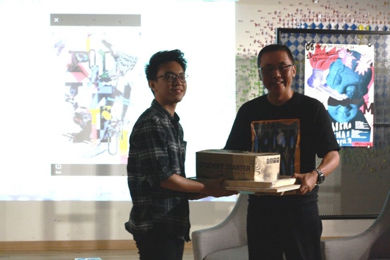 Yehezkiel Penalosa menerima hadiah dari Irwan Harnoko, ketua WGD, sebagai karya mahasiswa terbaik dalam Poster Exhibition 2018 DKV UPH