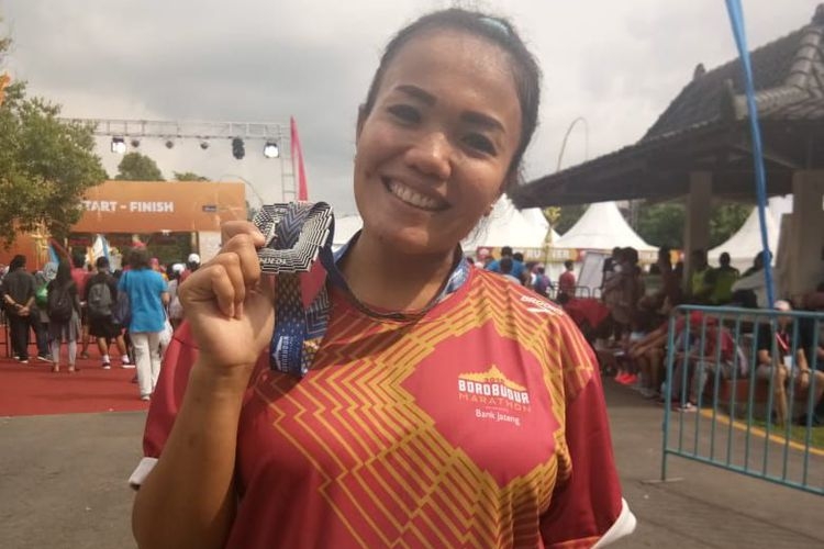 Kristine Sihotang (36), pelari asal Semarang, bangga menunjukkan medalinya, usai menyelesaikan lari 10K dalam ajang, Borobudur Marathon 2018, Minggu (18/11/2018). Sekalipun saat ini tengah hamil delapan bulan, Kristine mengaku tidak kesulitan untuk berlatih ataupun lomba lari. 