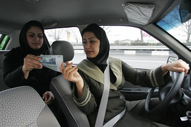 Ilustrasi: Seorang penumpang taksi di Iran menyerahkan pembayaran ke sopir yang juga perempuan (Sumber: gettyimages.com)