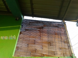 Tirai bambu dicat dengan oli bekas sebelum dipasang (dok.pri)