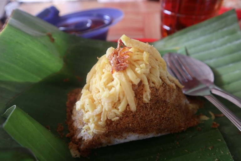 Nasi kebuli yang dibungkus daun pisang, lengkap dengan irisan telur dadar, rabuk ikan haruan dan taburan bawang goreng (dokpri)