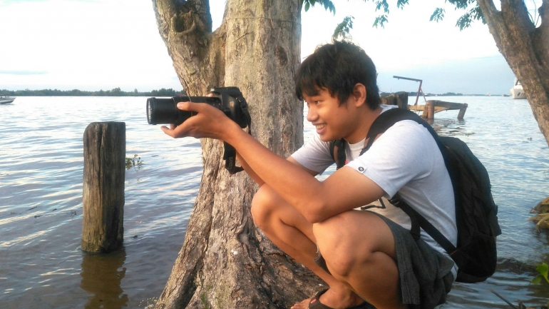 Seorang fotografer, Hans Richard, sedang memotret sunset atau matahari terbenam menjelang senja.