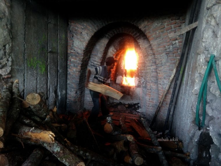 Seorang tukang sedang memasukkan kayu bakar ke tungku jobongan. Dokpri