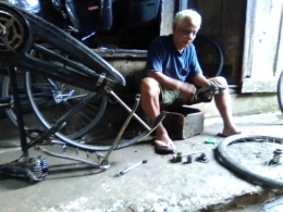 Pak Sarjiyo (76 tahun) sedang memperbaiki kerusakan sepeda saya di lapaknya di Pasar Burung atau ex Koplak Dokar. Dokpri 