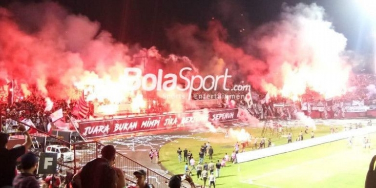 Flare menyala di tribun suporter Bali United. (Bolasport.com/Moch Hary Prasetya)