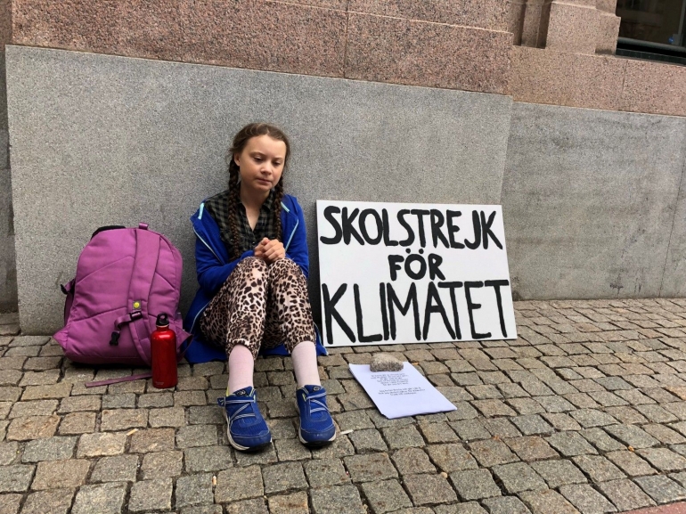 Gamabr 1. Seorang bocah sedang duduk di depan gedung parlemen Swedia (Sumber : Medium.com)