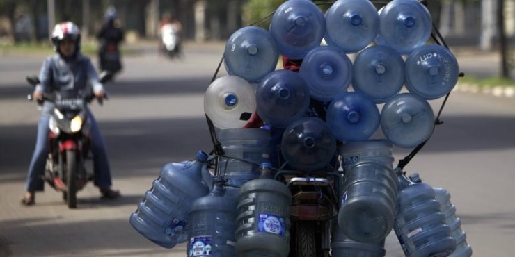 Ilustrasi: Pekerja membawa galon minuman air minum dengan saling diikat di atas sepeda motor. (KOMPAS/AGUS SUSANTO)