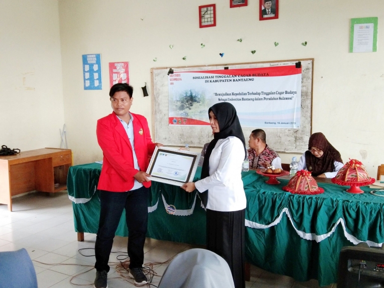 Kordes KKN UNHAS Gelombang 100 (kiri) serahkan sertifikat usai sosialisasi terkait pelestarian cagar budaya (16/01/2019).