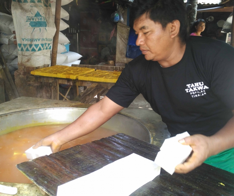 Salah seorang karyawan memasukkan tahu yang sudah dipotong ke dalam air rebusan yang kedua, yakni campuran pewarna makanan alami, garam dan bunga pekak kering (foto: Luana Yunaneva)