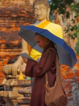 Seorang biksu yang mengenakan payung biru di Ayutthaya sedang memegang ipad (dokumentasi pribadi)