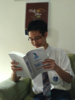 Rionanda sedang menikmati buku yang diterbitkan Bank Indonesia, yang di dalamnya terdapat salah satu tulisannya. (dok. Rudi Wijaya)