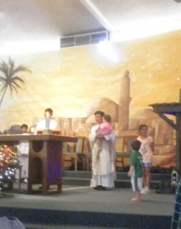 ket.foto" pertama kali dalam hidup,saya menyaksikan seorang Pastor mau mengendong seorang anak di depan altar /dokumentasi pribadi