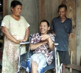 Samsudin didampingi bapak ibunya tertawa di atas kursi roda (foto: dok pri)