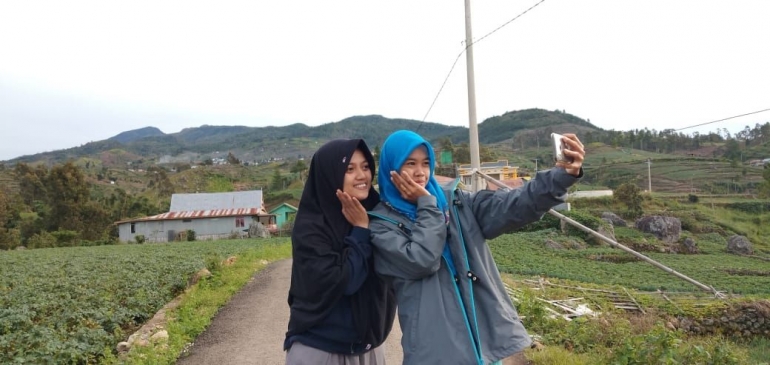 Swafoto berlatar belakang jalan dan ladang di dusun Muntea