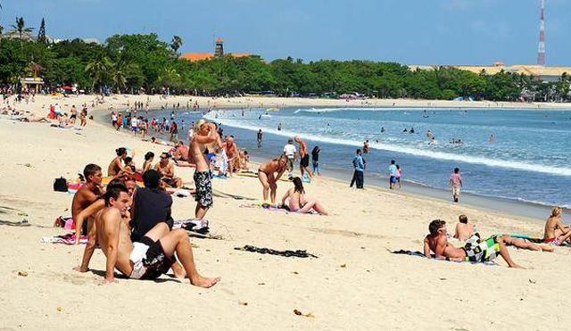 Turis di Bali menikmati sinar matahari di pantai berpasir (Sumber: balirealtyhv.com)