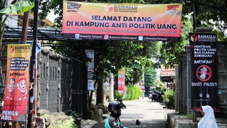 Poster berisi ajakan untuk menolak politik uang dan suap serta untuk mengawasi proses pemilu terpasang di Kampung Antipolitik Uang di Parigi, Pondok Aren, Tangerang Selatan, Kamis (4/4/2019). (KOMPAS/HERU SRI KUMORO)