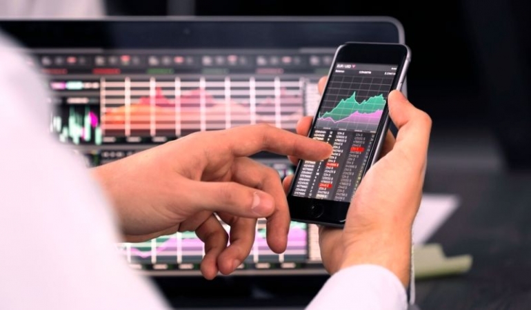 Investasi saham dengan gadget di genggaman tangan (Foto: Shutterstock)