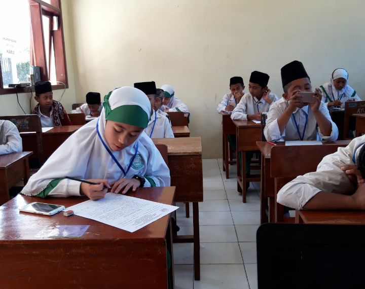 Siswa Madrasah Ibtidaiyah ( setingkat SD) sedang berkonsentrasi mengerjakan soal ujian Nasional