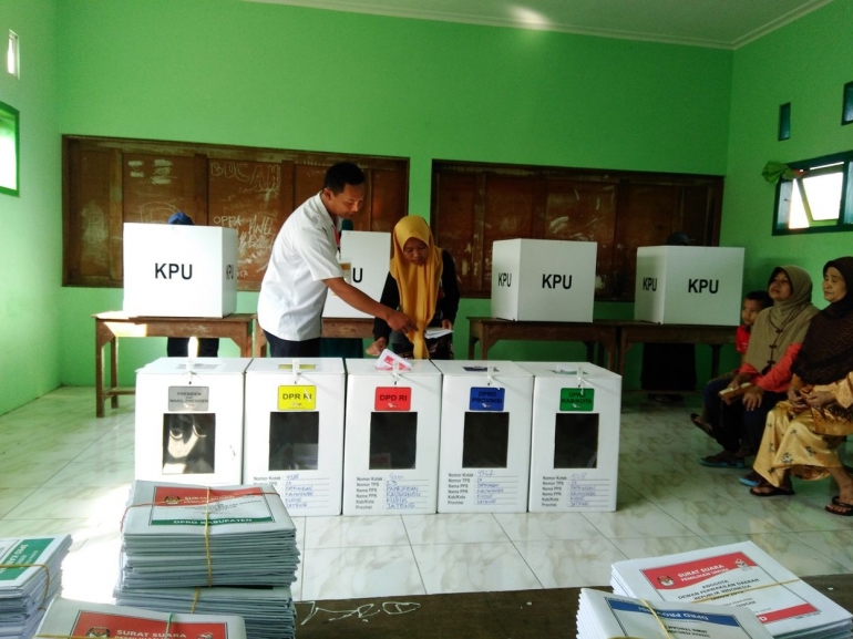 Seorang pemilih dipandu oleh anggota KPPS untuk memasukan surat suara ke kotak yang tepat/dokpri