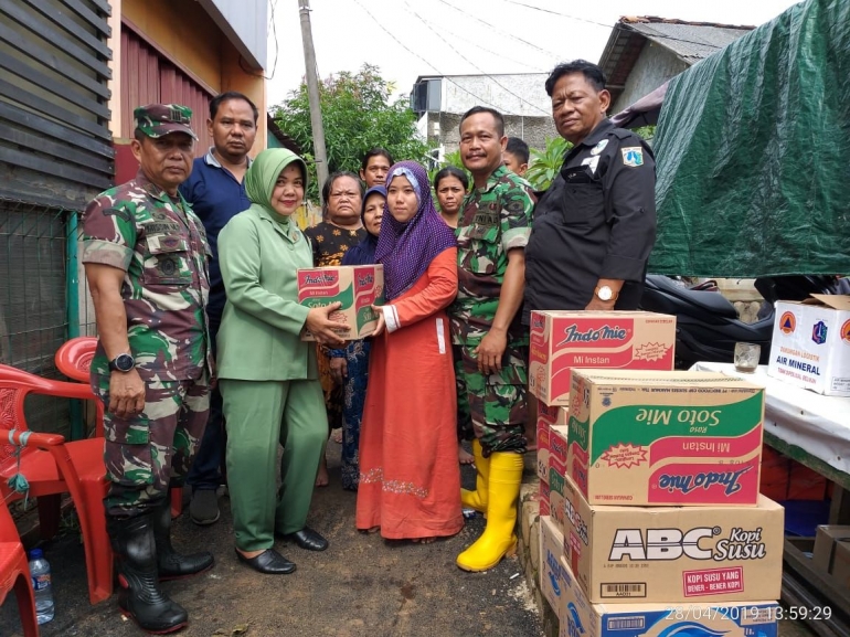 Ketua Persit KCK Ranting VIII Koramil 07/KB Ny. Ida Nurhayati Misin MD sedang berikan bantuan korban banjir didampingi Danramil 07/Kembangan Kapten Inf Misin MD