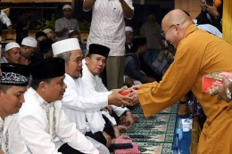 Seorang biksu membagikan takjil kepada umat Islam yang berpuasa i